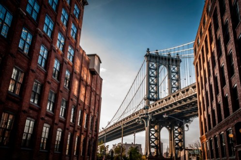 Image de Manhattan bridge seen from a narrow alley enclosed by two brick buildings on a sunny day in summer