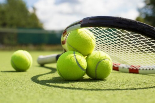 Picture of Tennis balls and racket on the grass court