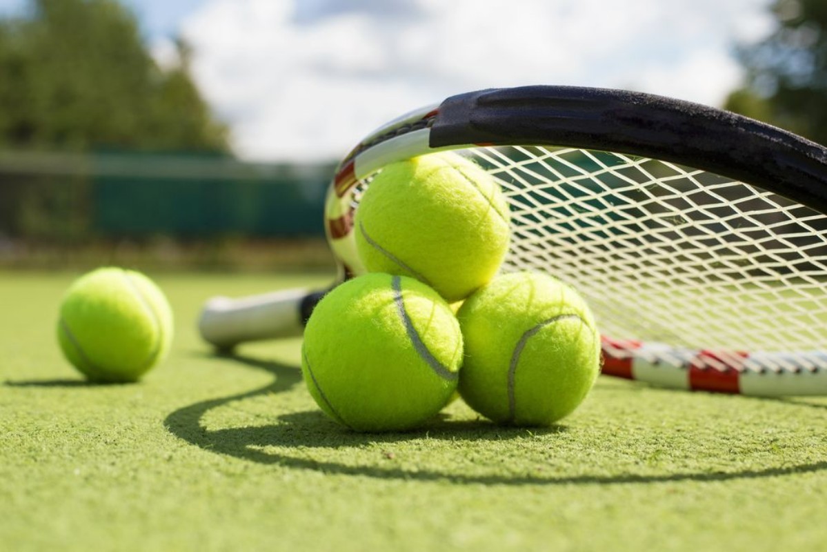 Afbeeldingen van Tennis balls and racket on the grass court