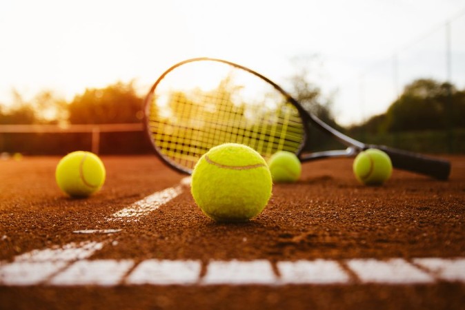 Bild på Tennis balls with racket on clay court