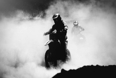 Picture of Motocross racer accelerating in dust track Black and white hig