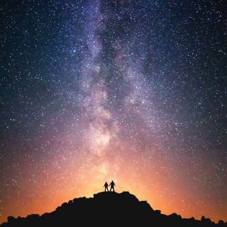 Bild på Universe for two Silhouettes of two people standing together holding hands against the Milky Way on the top of the hill