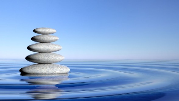 Picture of Zen stones stack from large to small  in water with circular waves and blue sky