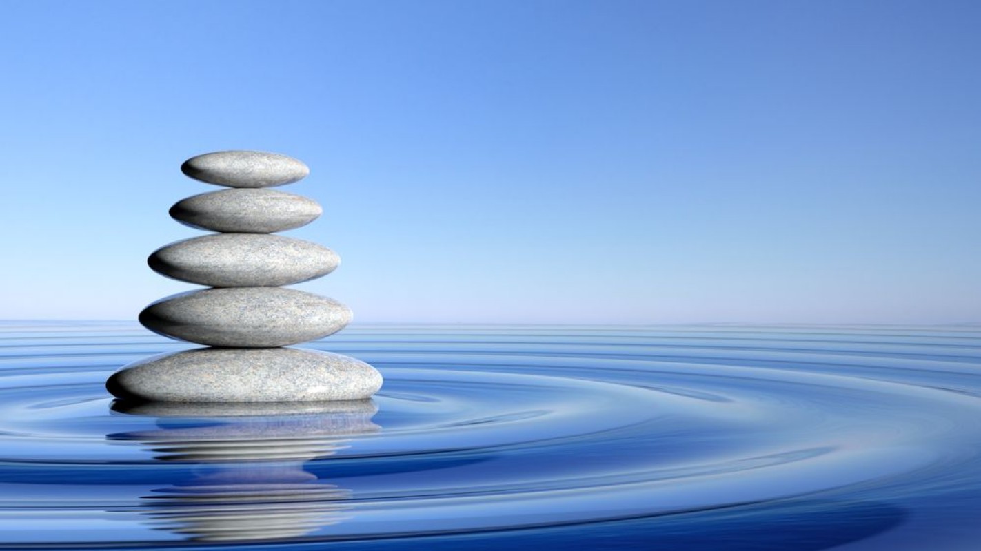 Image de Zen stones stack from large to small  in water with circular waves and blue sky