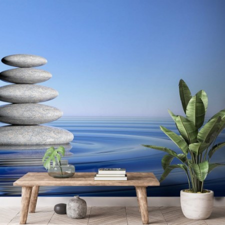Afbeeldingen van Zen stones stack from large to small in water with circular waves and blue sky