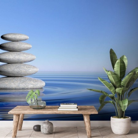 Imagem de Zen stones stack from large to small in water with circular waves and blue sky